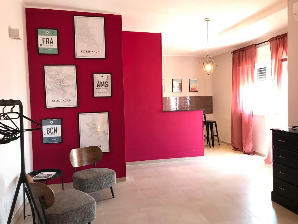 a red wall in a living room with chairs at Apartment Antonella in Ostuni