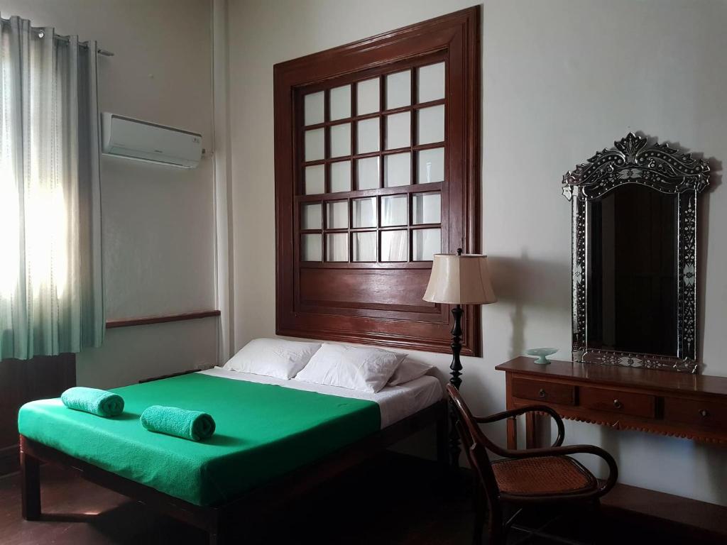 1 dormitorio con cama verde, ventana y espejo en Casa Tentay en Iloílo