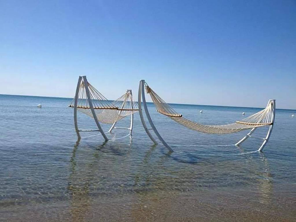 two hammocks sitting in the water on a beach at Villa Cenzina in Marina di Pisticci