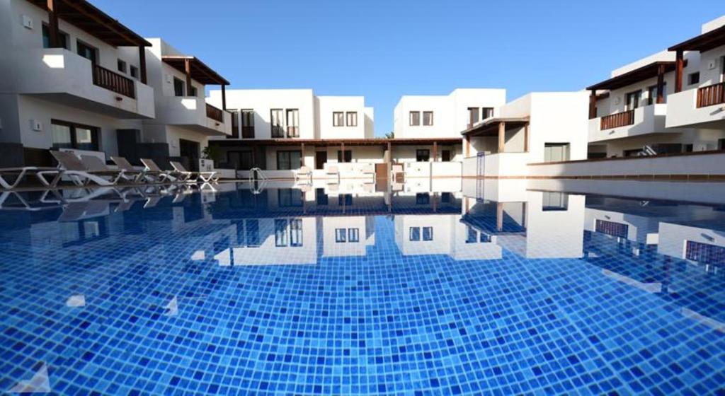 a swimming pool with blue tiles in front of buildings at Casa Zen in Puerto Calero
