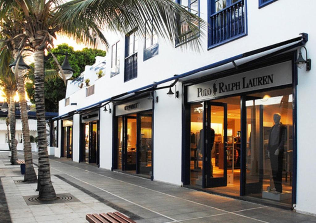 a row of store fronts on a street with a palm tree at Casa Zen in Puerto Calero