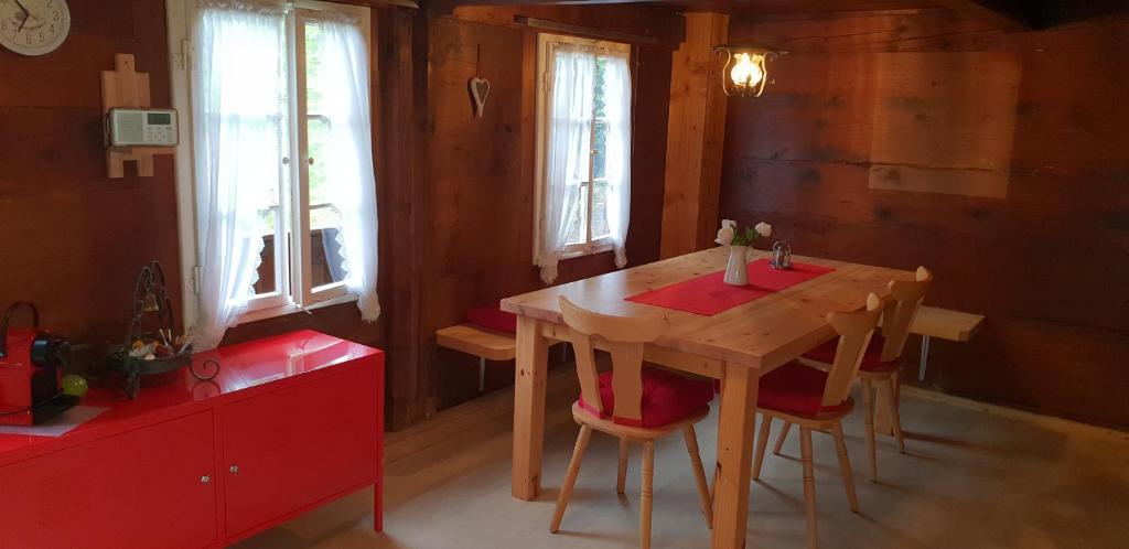 una mesa de madera y sillas en una habitación con ventanas en Wettermatte en Kiental