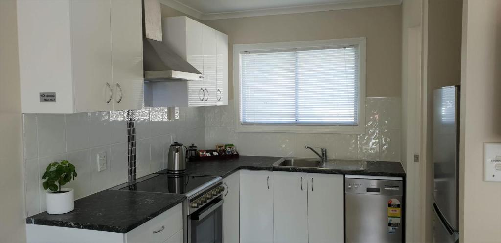uma cozinha com armários brancos e um balcão preto em Rose Apartments Unit 3 Central Rotorua - Accommodation & Spa em Rotorua