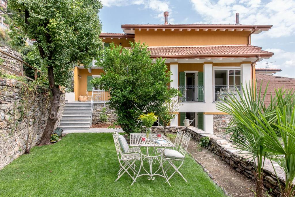 einen Garten mit einem Tisch und Stühlen vor einem Haus in der Unterkunft Residenza La Zagara in Cannero Riviera