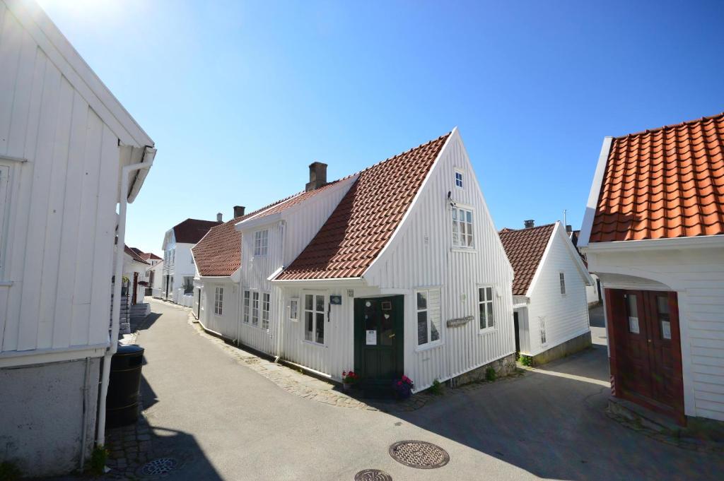 eine Reihe weißer Häuser mit roten Dächern auf einer Straße in der Unterkunft Reinertsenhuset in Skudeneshavn