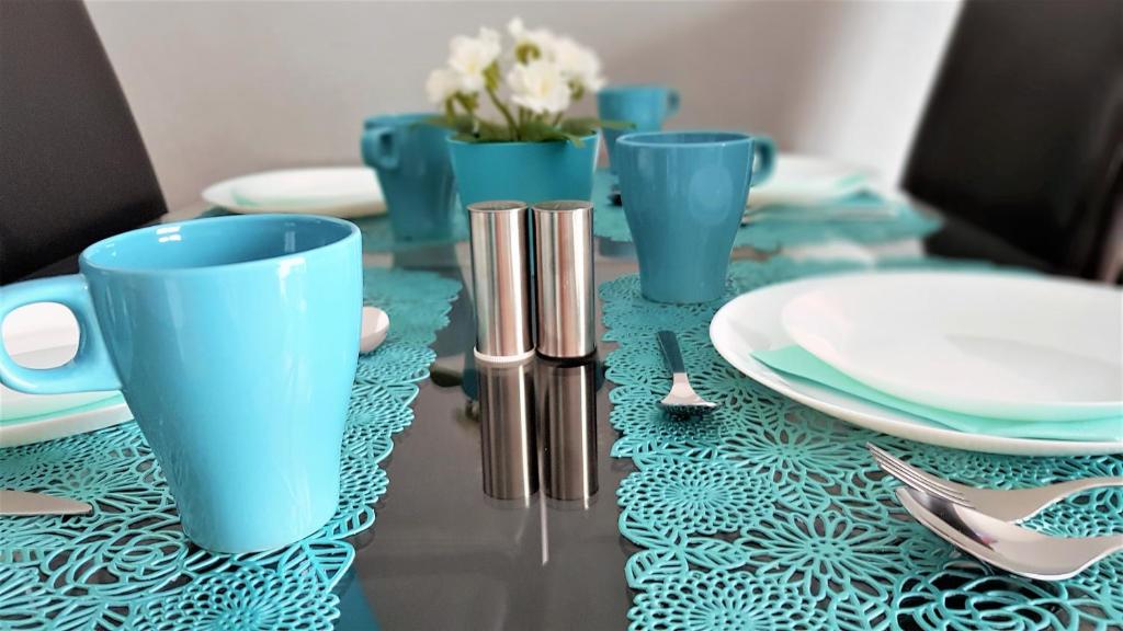a table with blue cups and plates on a table at Apartament B&F Garbary Poznań Business & Family - Parking in Poznań