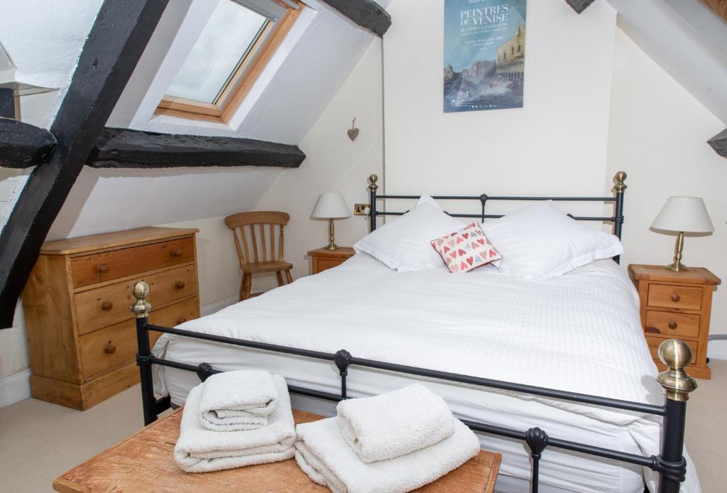 a bedroom with a bed with towels on a table at Half-pint Cottage in Stroud