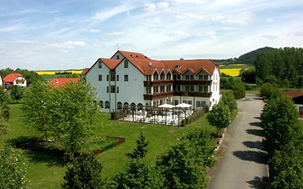 einen Luftblick auf ein großes weißes Haus mit einer Straße in der Unterkunft Hotel Restaurant Goger in Haßfurt
