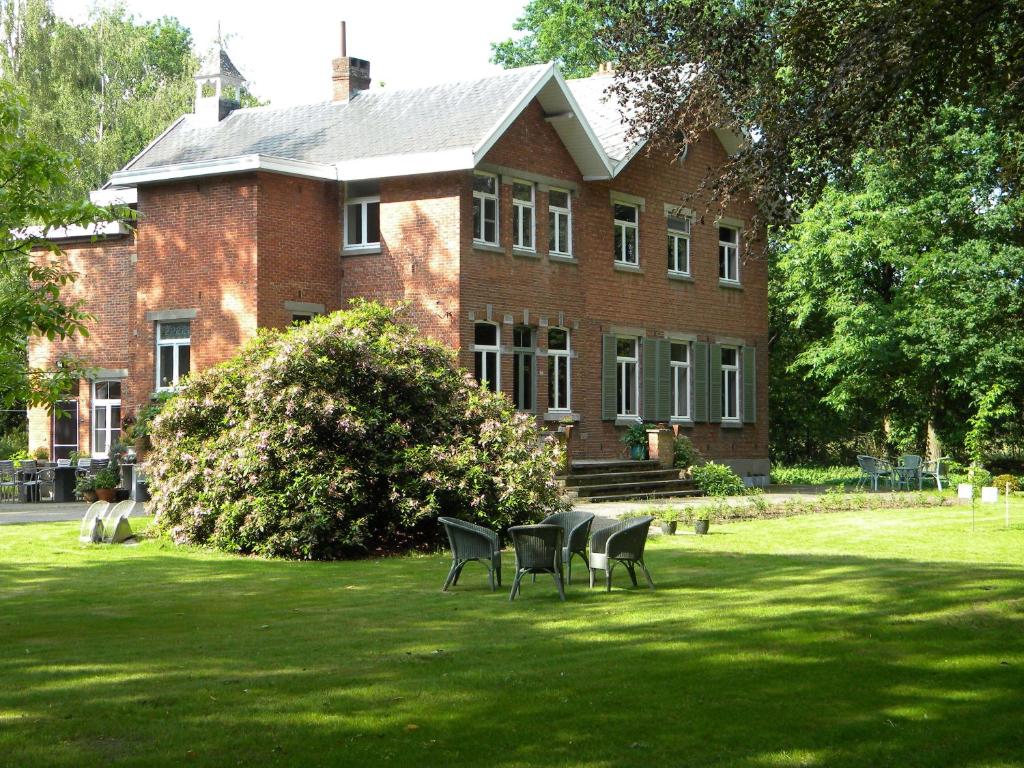 une maison avec des chaises dans l'herbe devant elle dans l'établissement B&B Le Refuge, à Hasselt