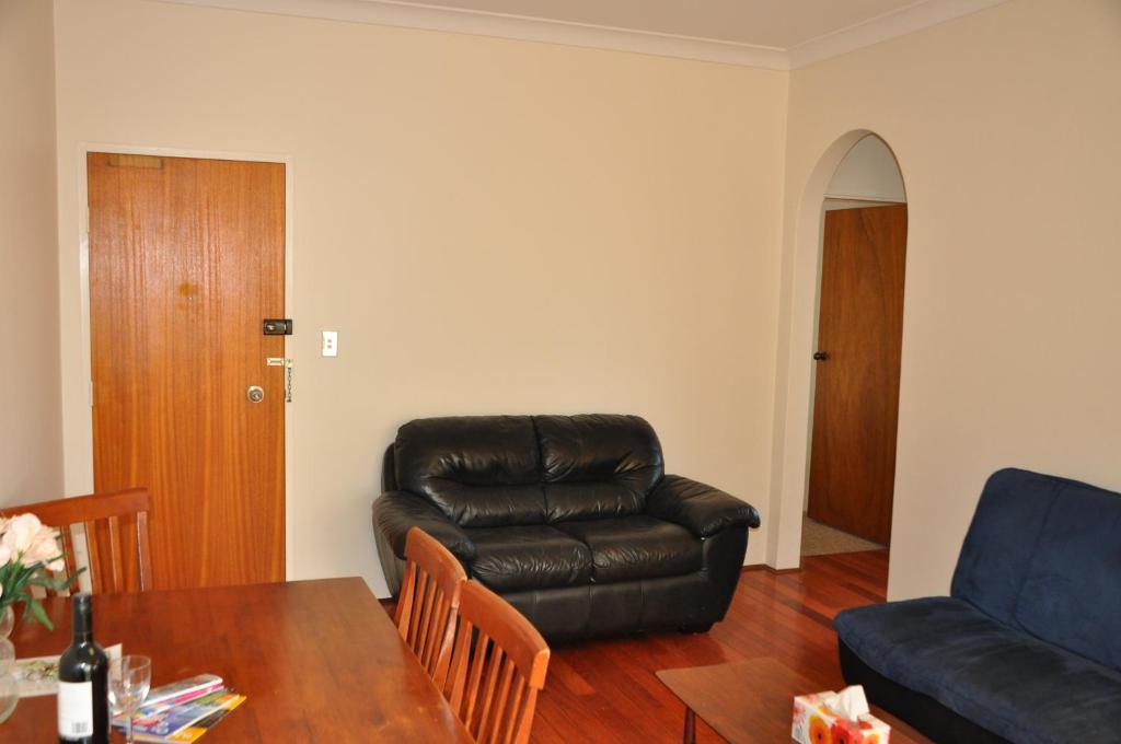 a living room with a leather couch and a table at Accommodation Sydney Kogarah 2 bedroom apartment with balcony in Sydney