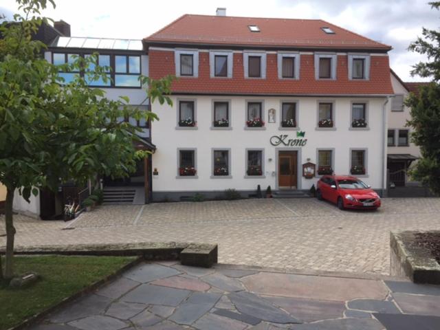 een rode auto geparkeerd voor een gebouw bij Hotel & Gästehaus Krone in Geiselwind