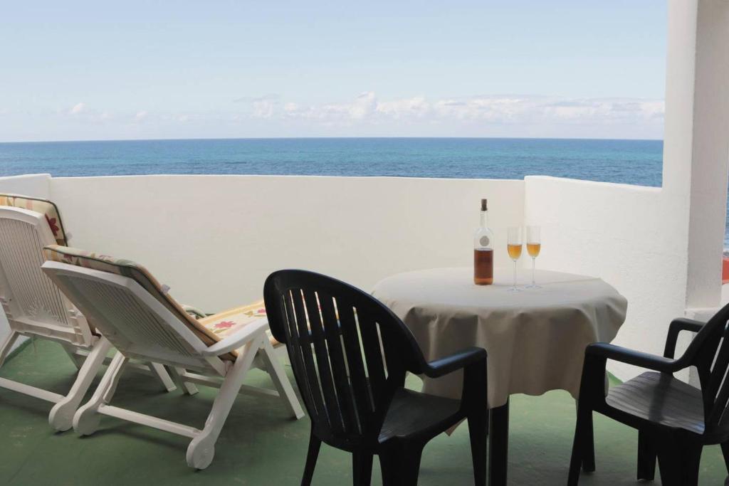 uma mesa com duas cadeiras e uma garrafa de vinho em Oasis Atlántico: rincón secreto al pie de los senderos em Azano