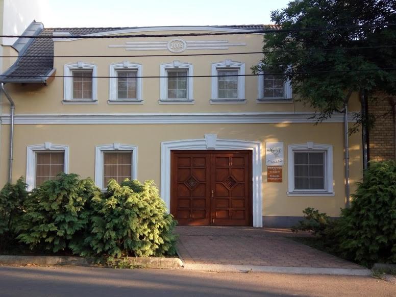 ein großes Haus mit brauner Tür und einigen Büschen in der Unterkunft Hubertus Panzió in Csongrád