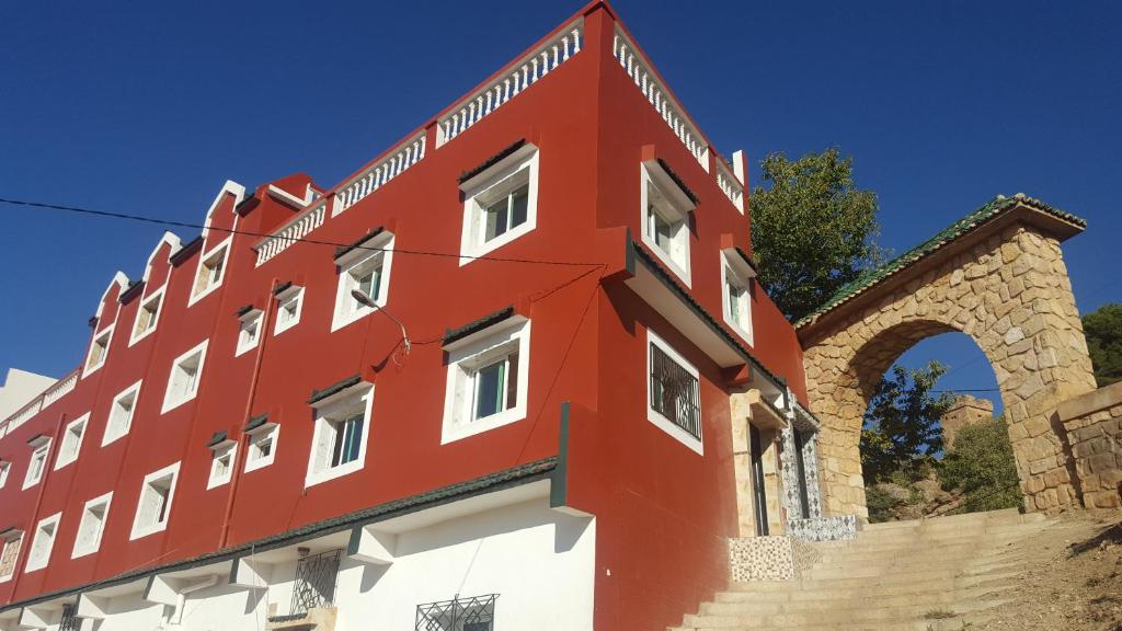 a red and white building with an arch at Hotel Ain Leuh in Aïn Leuh