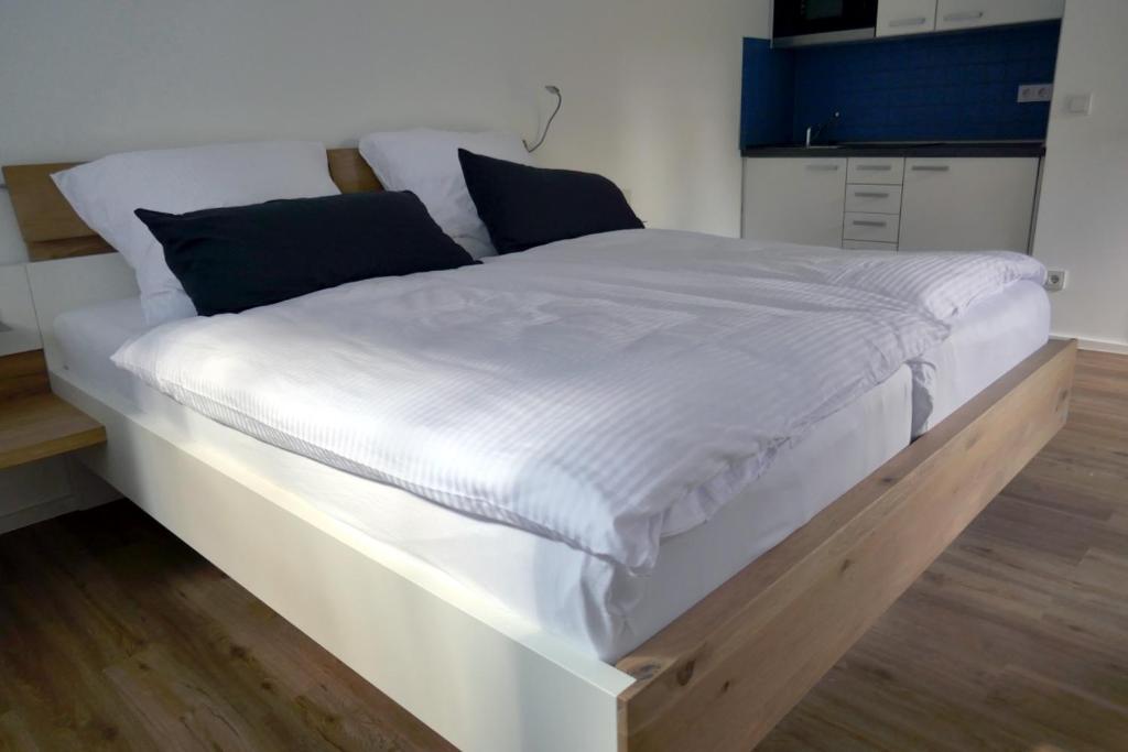 een groot wit bed met een houten frame in een kamer bij Messeappartement Unterrath in Düsseldorf