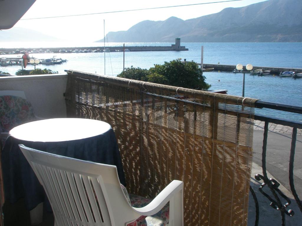 a table and a chair on a balcony overlooking the water at Apartments Dorcic in Baška