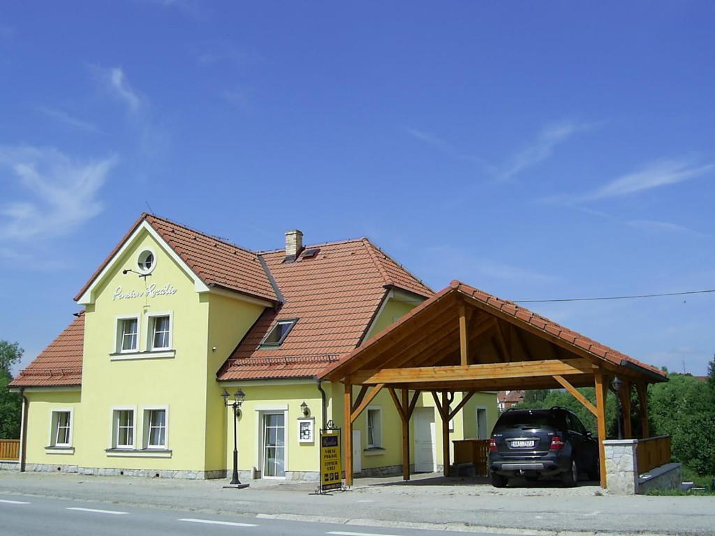 ein großes gelbes Gebäude mit einem Holzdach in der Unterkunft Penzion Rozalie in Horní Planá