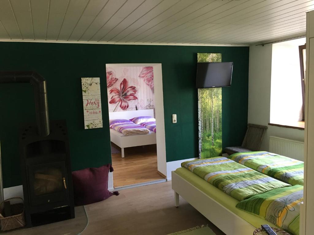 a room with two beds and a fireplace and green walls at Anita's Zimmer in Engelhartszell