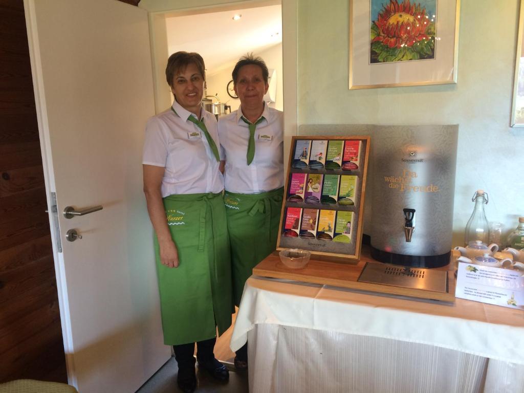 two women are standing next to a table with a display at Hotel Garni Wurzer in Velden am Wörthersee