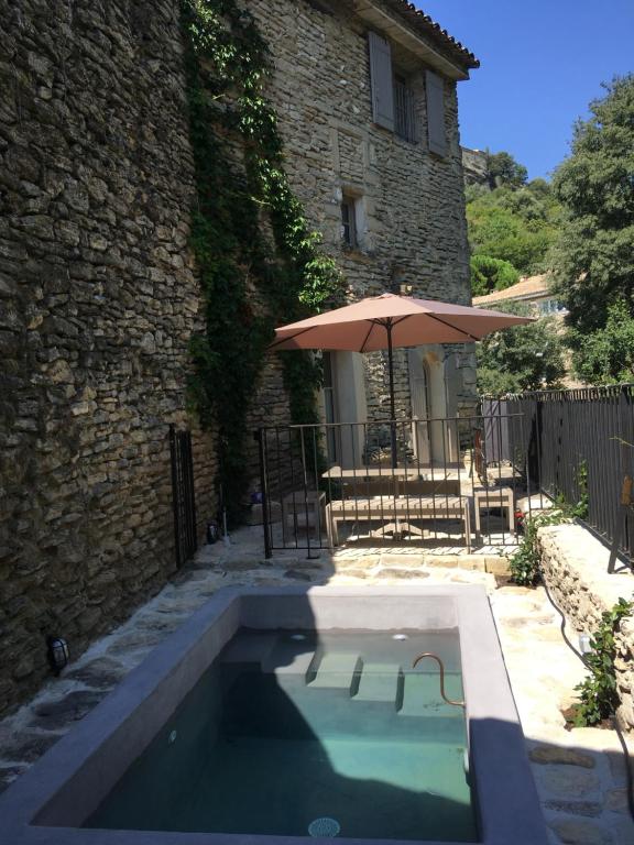 a swimming pool in front of a building with an umbrella at La Calade, maison de village in Gordes