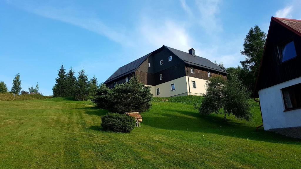 a large black and white building on a grass field at Chaloupka Slaměnka in Loučná pod Klínovcem