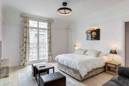 um quarto branco com uma cama e um sofá em Appartement Champs Elysées em Paris
