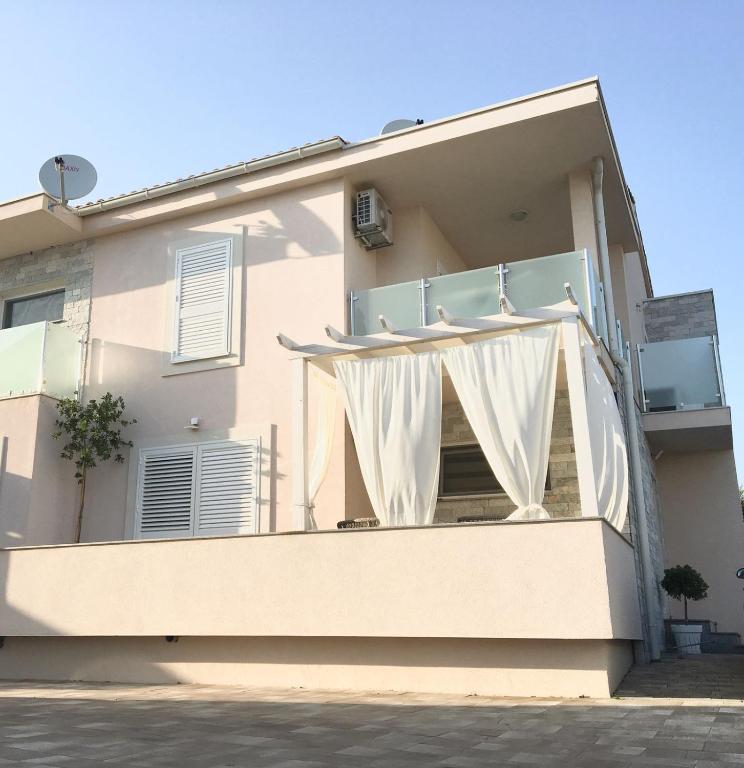 a white house with a balcony with a white curtain at Apartment Josip 2 in Tribunj