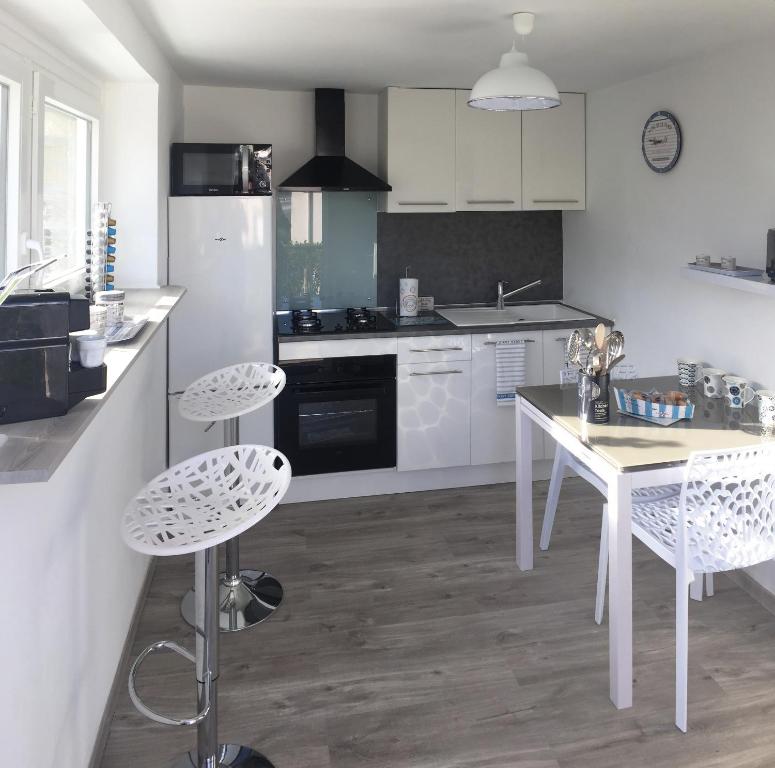 a kitchen with white cabinets and a white table and chairs at Cosy's'Plage in Kerderff