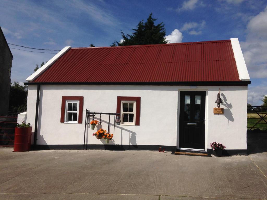 un pequeño edificio blanco con techo rojo en 'Uncle Owenie's Cottage', en Crossmaglen