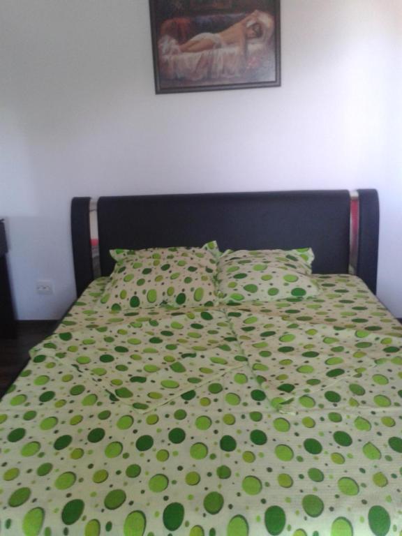 - un lit avec une couette et des oreillers verts dans l'établissement Villa ALEX, à Slatina