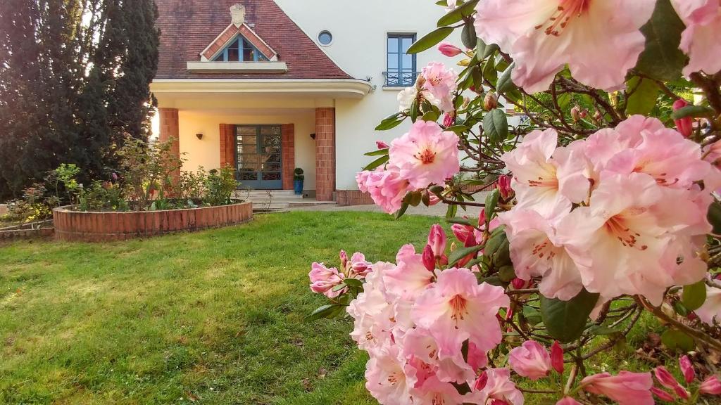 un arbusto de flores rosas delante de una casa en La Closerie, en Droue-sur-Drouette