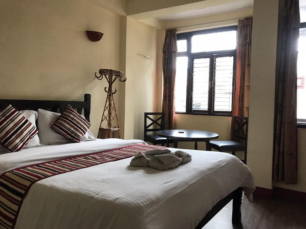 a bedroom with a bed and a table and a window at Hotel Yala Peak in Kathmandu