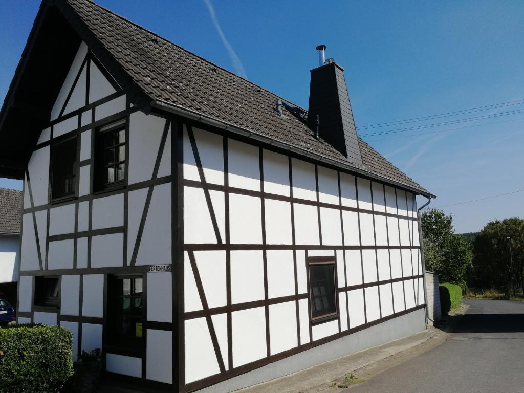 een wit en zwart gebouw met een zwart dak bij Eifel Ferienhaus Luna in Ohlenhard