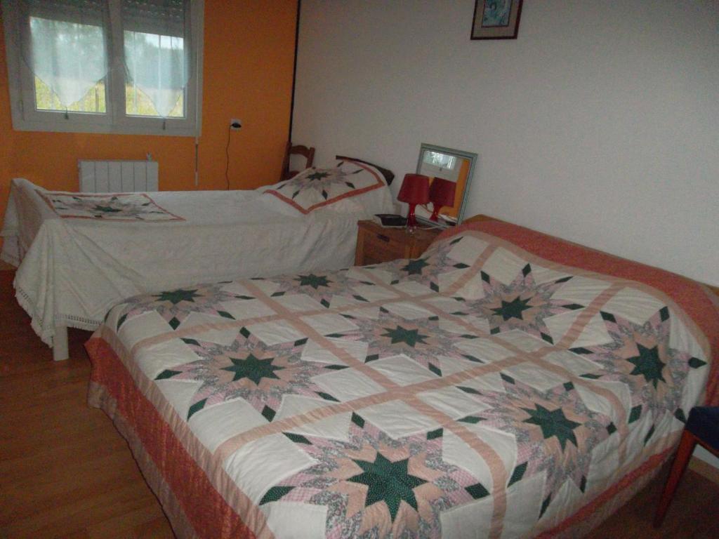 sypialnia z 2 łóżkami i kołdrą na łóżku w obiekcie Les Chambres Du Rochereuil w mieście Bédée