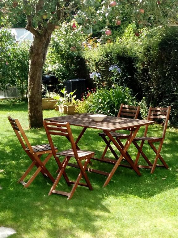 - une table de pique-nique en bois et 2 chaises dans l'herbe dans l'établissement Maison de vacances cosy, à Avranches