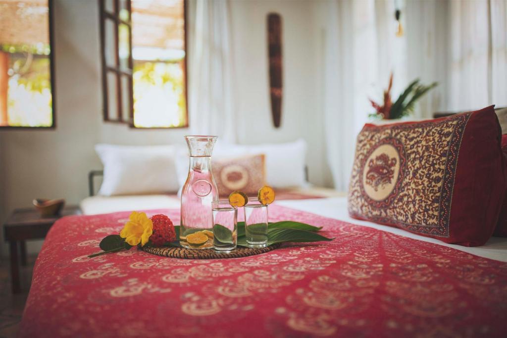 une table avec un tissu de table rouge, une bouteille et des fleurs dans l'établissement Encantada Ocean Cottages, à Esterillos Este