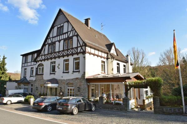 um grande edifício com carros estacionados em frente em Bielefelder Berghotel zum Stillen Frieden em Bielefeld