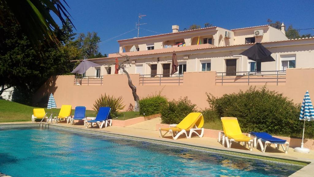 a pool with chairs and a house in the background at Falfeira Apartments in Lagos