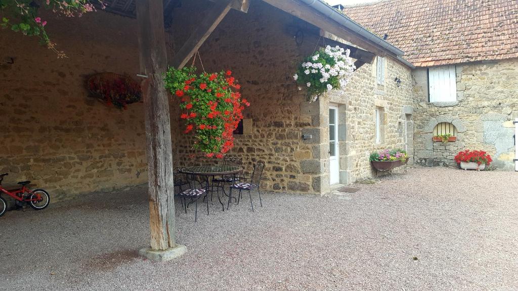 una mesa y sillas con flores colgando de un edificio en Cottage 2 personnes, en Lormes