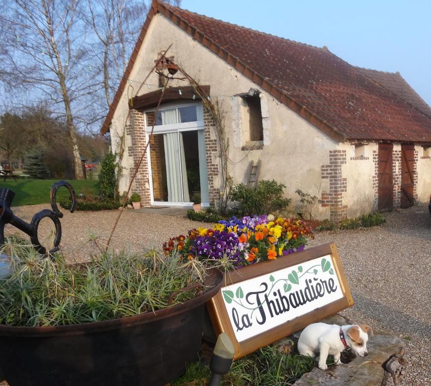 a dog laying in front of a house with a sign at Gîte La Thibaud in Lavernat