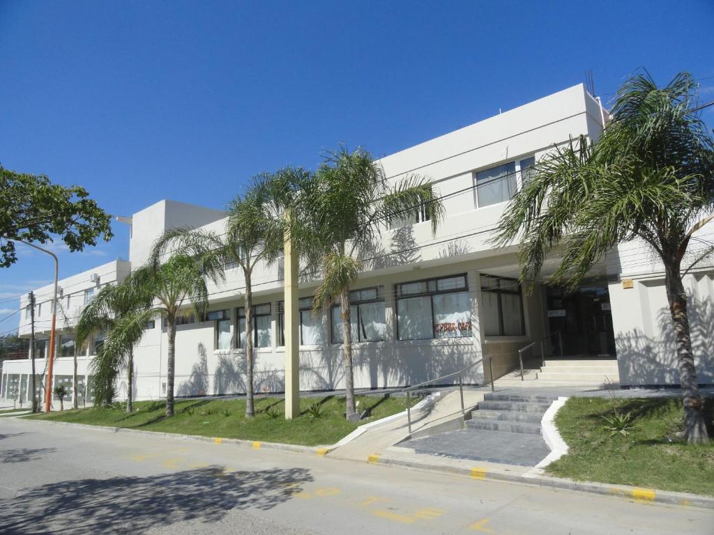 a white building with palm trees in front of it at Hotel La Fontana in Termas de Río Hondo