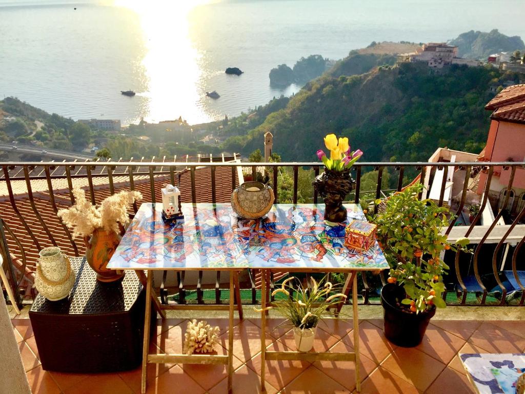 una mesa en un balcón con vistas al agua en Maison belle Vue, en Taormina