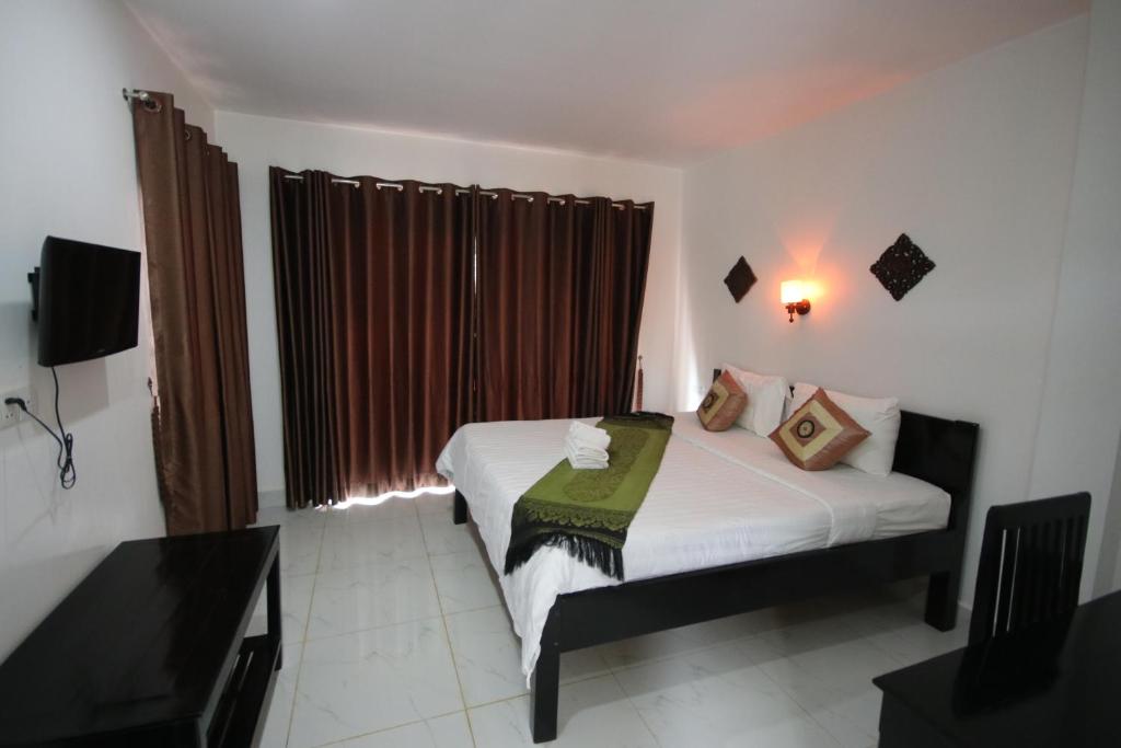 una camera da letto con un letto e una finestra con tende di Green Life Cottage a Siem Reap