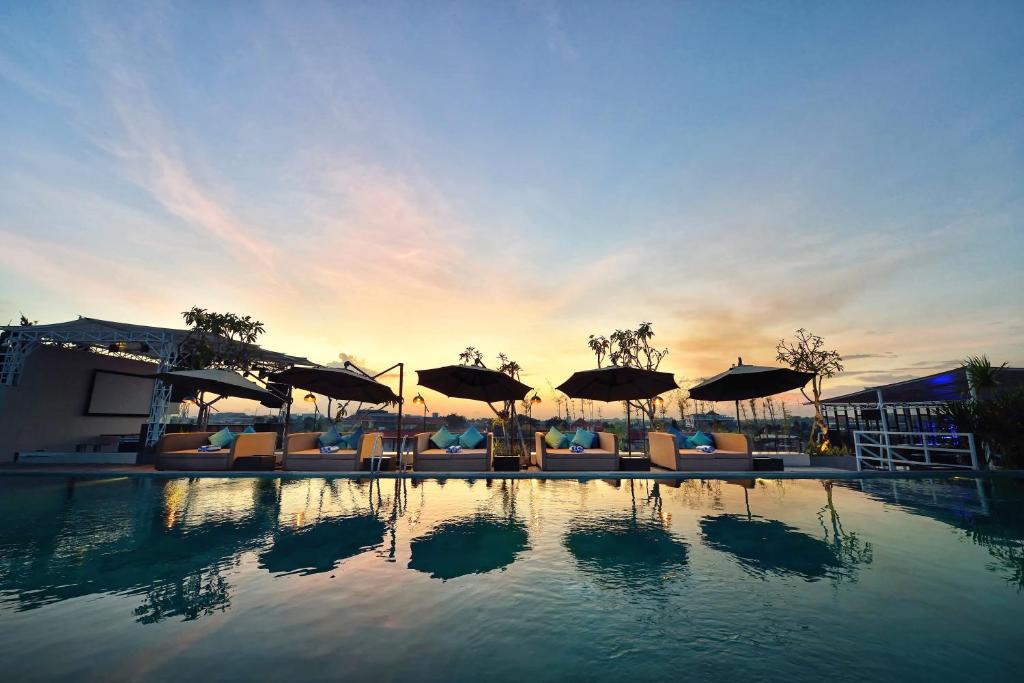 a pool with chairs and umbrellas in a resort at de Vins Sky Hotel Seminyak in Seminyak