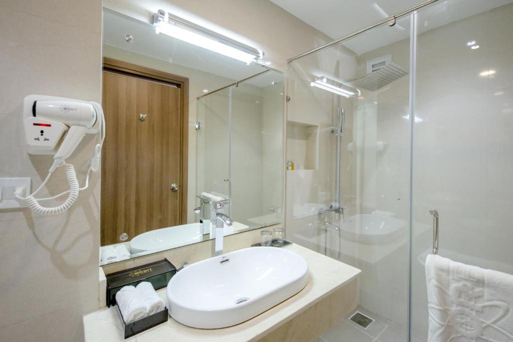 uma casa de banho branca com um lavatório e um chuveiro em Orbit Hotel em Nha Trang