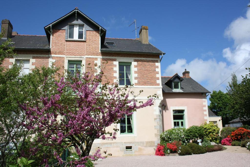Chambres d'Hôtes du Chalet de Caharet في Pipriac: منزل قديم وامامه زهور