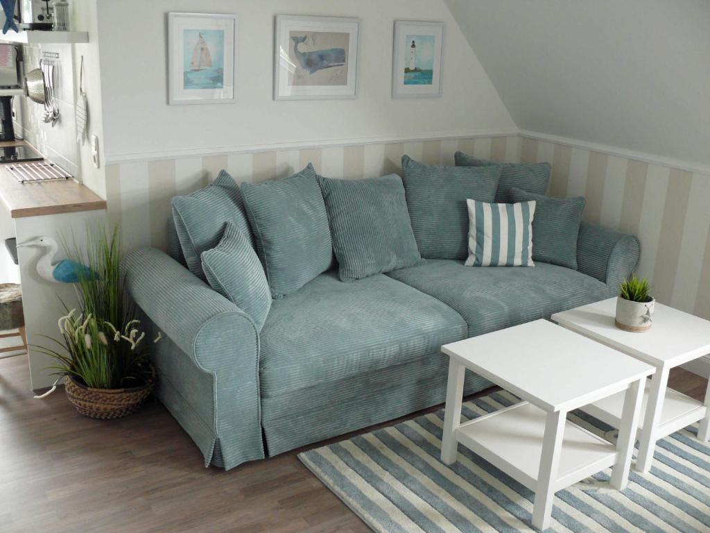 ein Wohnzimmer mit einem blauen Sofa und einem Tisch in der Unterkunft (WIK7a) in Niendorf