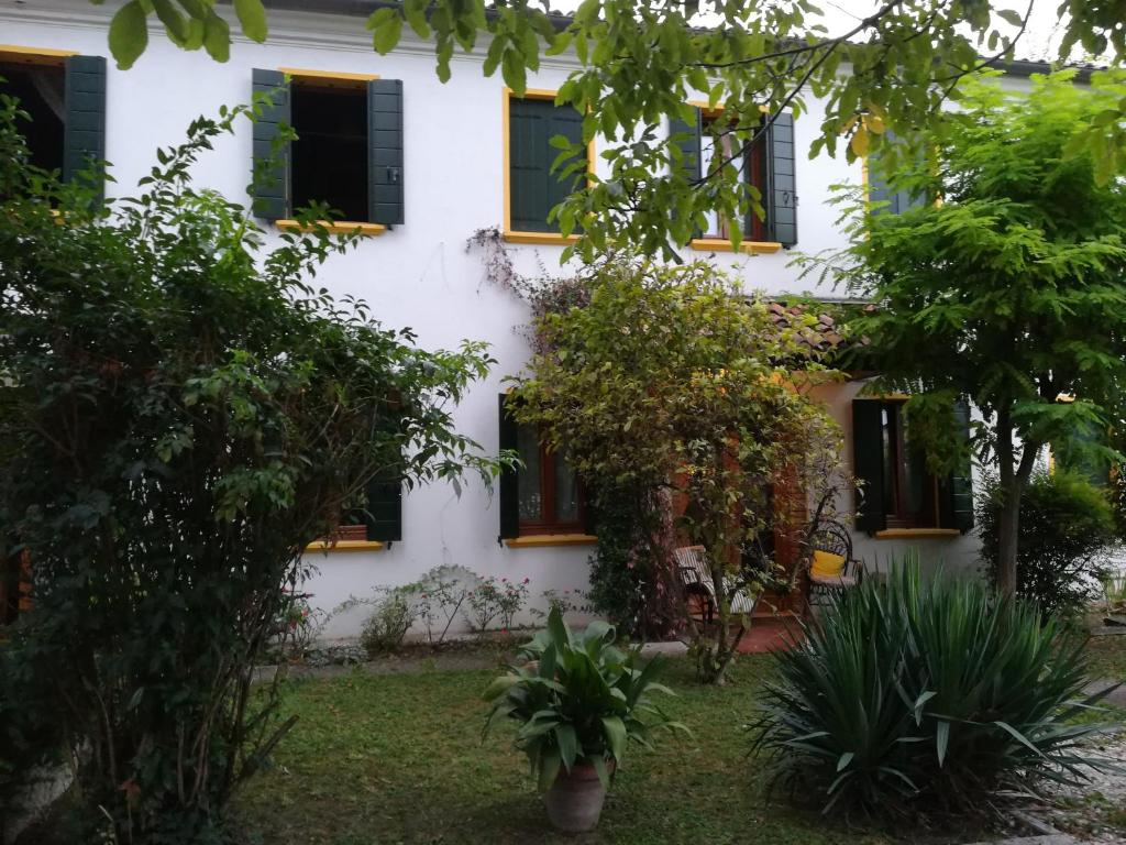 a white house with black windows and trees at Room Garden in Padova