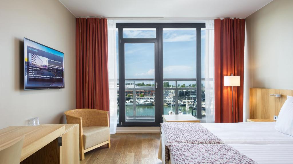 タリンにあるヘスティア ホテル ヨーロッパのベッドと大きな窓が備わるホテルルームです。