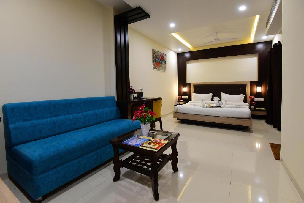 a living room with a blue couch and a bed at Hotel Dayal Shree Paradise in Bhopal